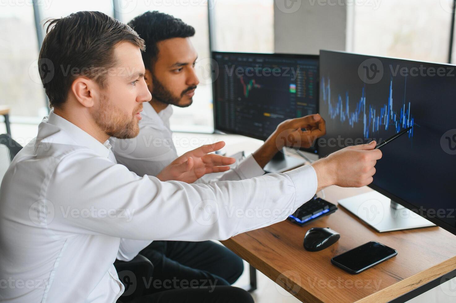 Two successful trader in formalwear pointing at display, analyzing stat and dynamic on forex charts, working in office together photo