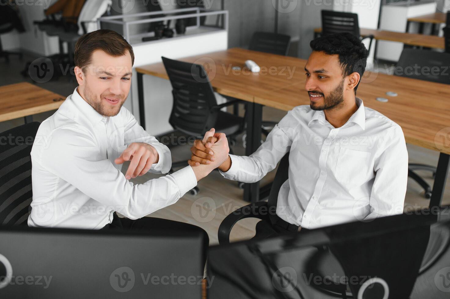 Two men traders sitting at desk at office together monitoring stocks data candle charts on screen analyzing price flow smiling cheerful having profit teamwork concept photo