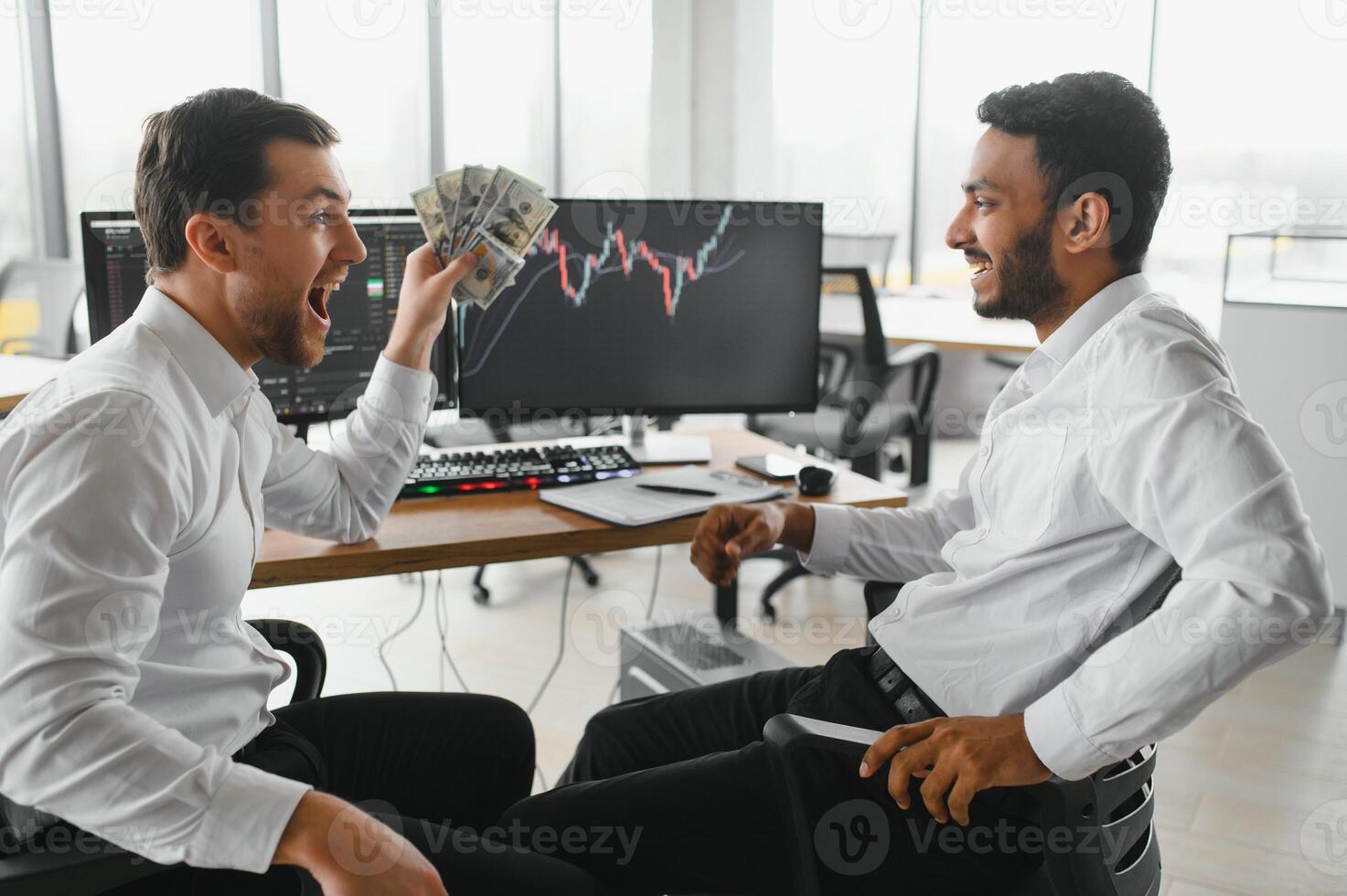 Two men traders sitting at desk at office together monitoring stocks data candle charts on screen analyzing price flow smiling cheerful having profit teamwork concept photo