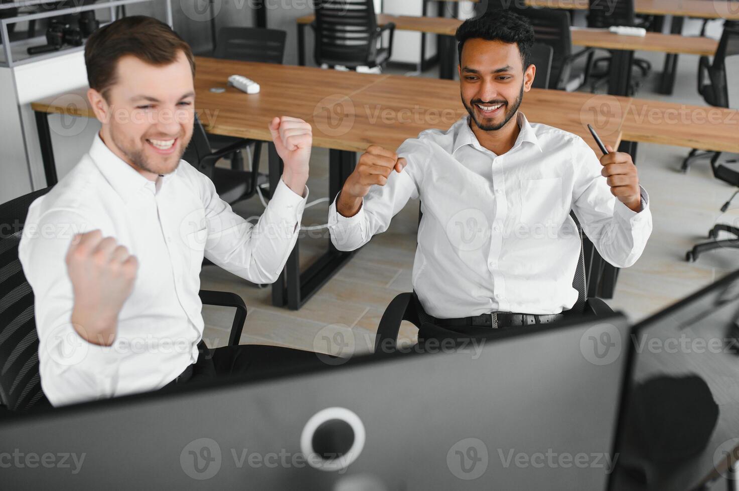 Two men traders sitting at desk at office together monitoring stocks data candle charts on screen analyzing price flow smiling cheerful having profit teamwork concept photo