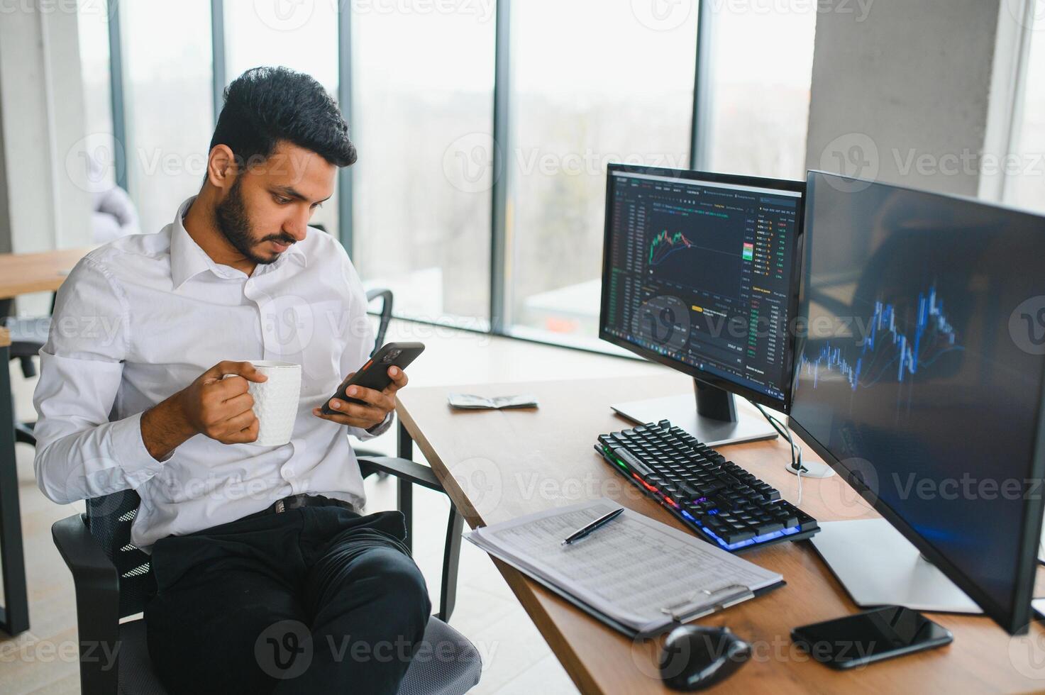 Thoughtful concentrated indian business man entrepreneur investor manager using computer, watching webinar working in office analyzing online data market thinking doing web research looking at laptop. photo