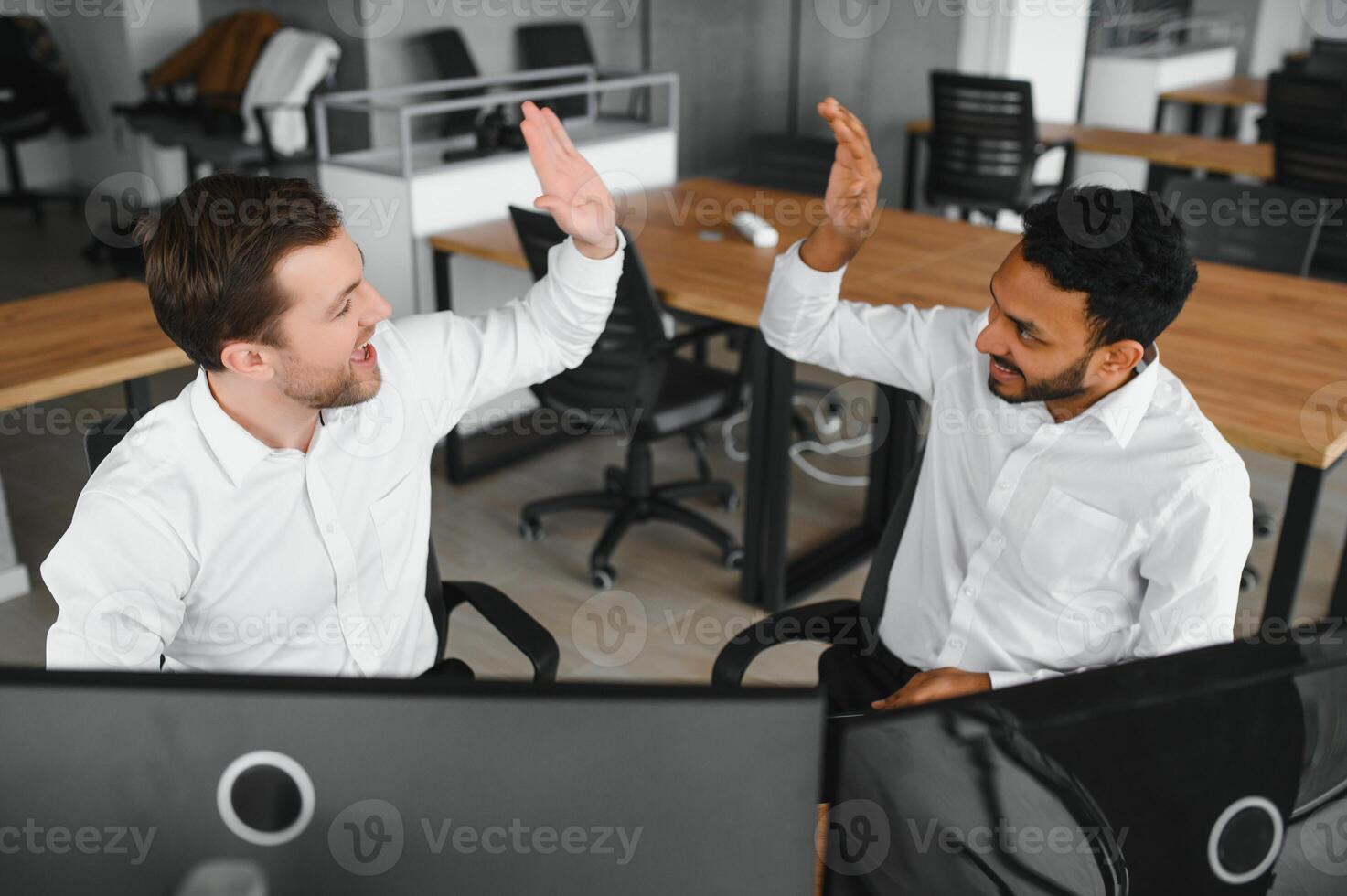 Two successful trader sitting in office and looking at screen, checking cryptocurrency information data on finance market graph, pointing on monitor photo