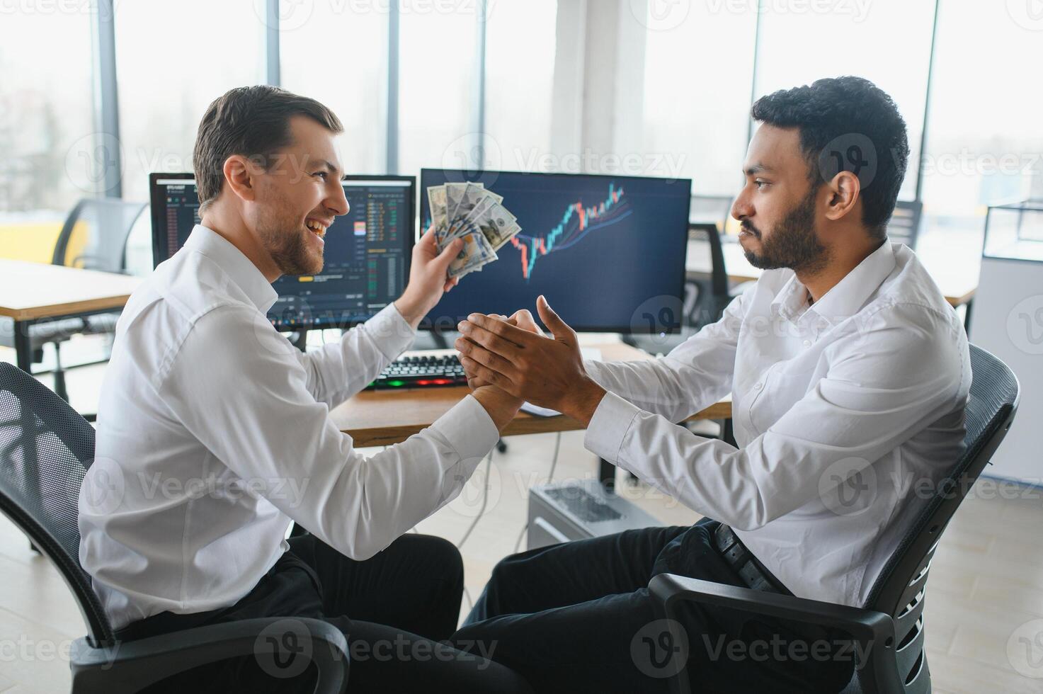 Two men traders sitting at desk at office together monitoring stocks data candle charts on screen analyzing price flow smiling cheerful having profit teamwork concept photo