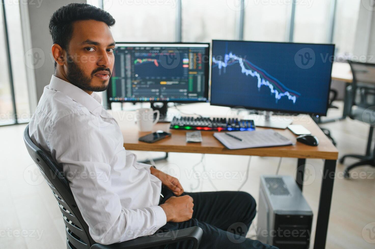 Thoughtful concentrated indian business man entrepreneur investor manager using computer, watching webinar working in office analyzing online data market thinking doing web research looking at laptop. photo