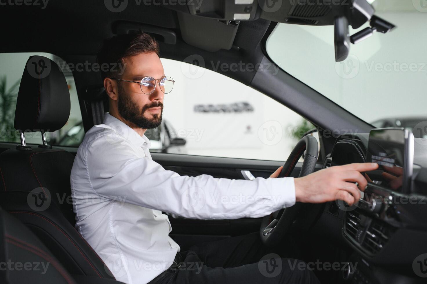 Happy caucasian man in formal wear getting inside luxury modern car for testing interior before purchase. Concept of dealership, selling and purchase photo