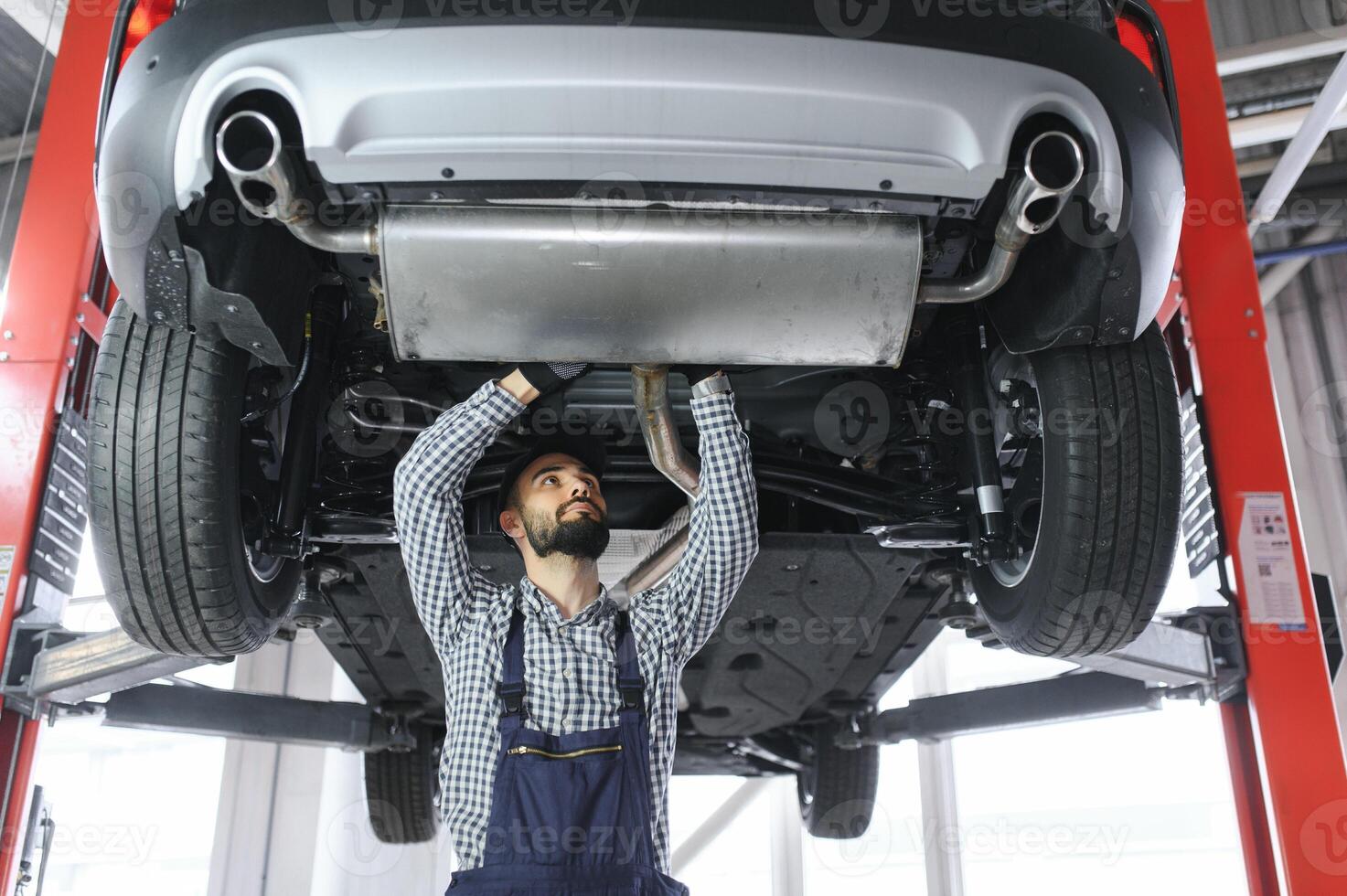 Portrait of a mechanic repairing a lifted car photo