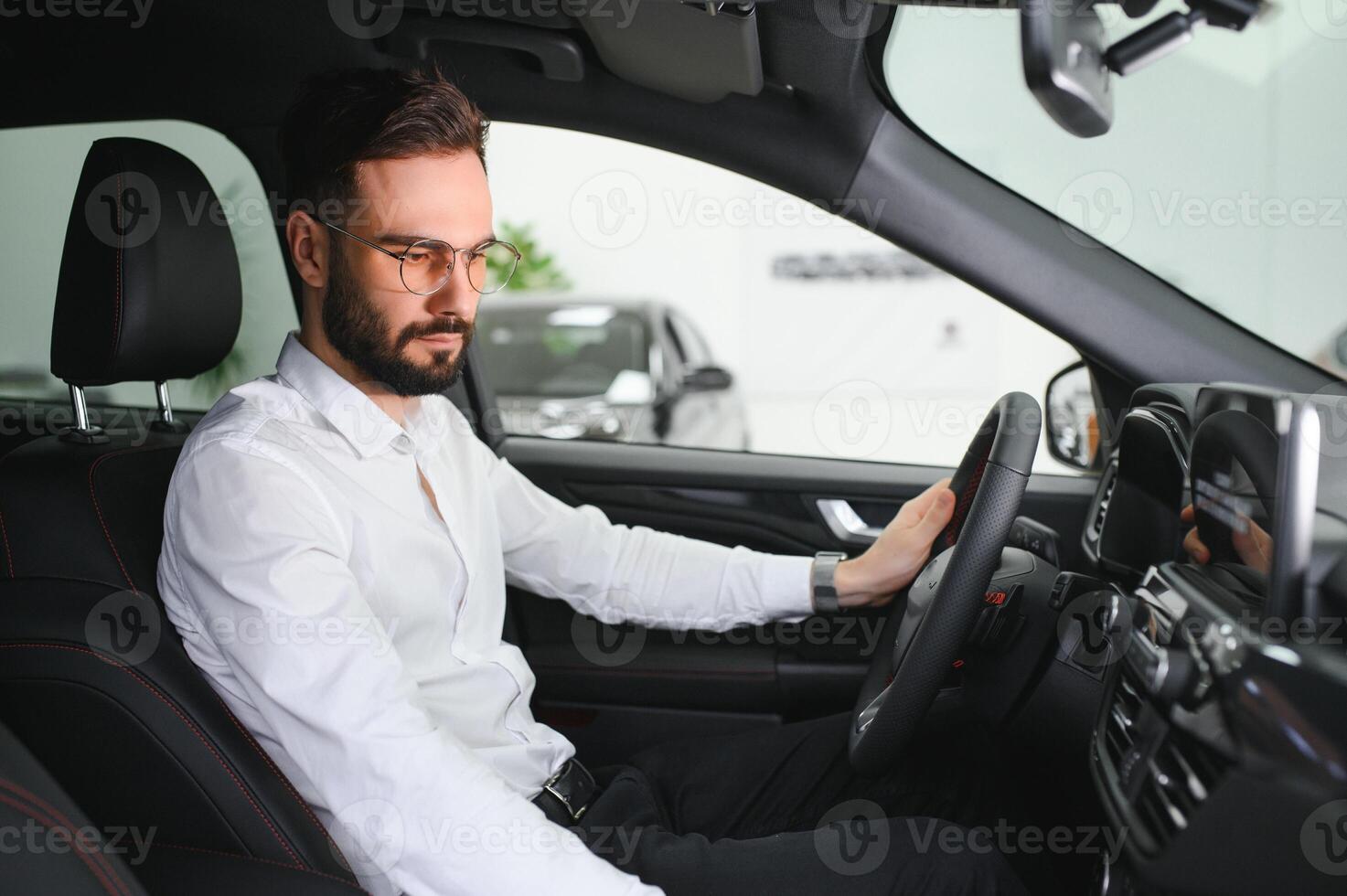 Happy caucasian man in formal wear getting inside luxury modern car for testing interior before purchase. Concept of dealership, selling and purchase photo