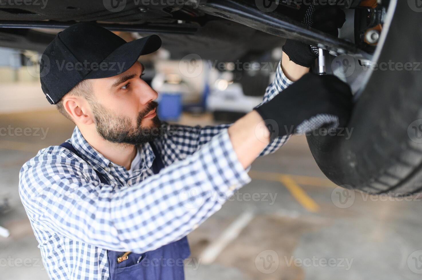 Portrait of a mechanic repairing a lifted car photo