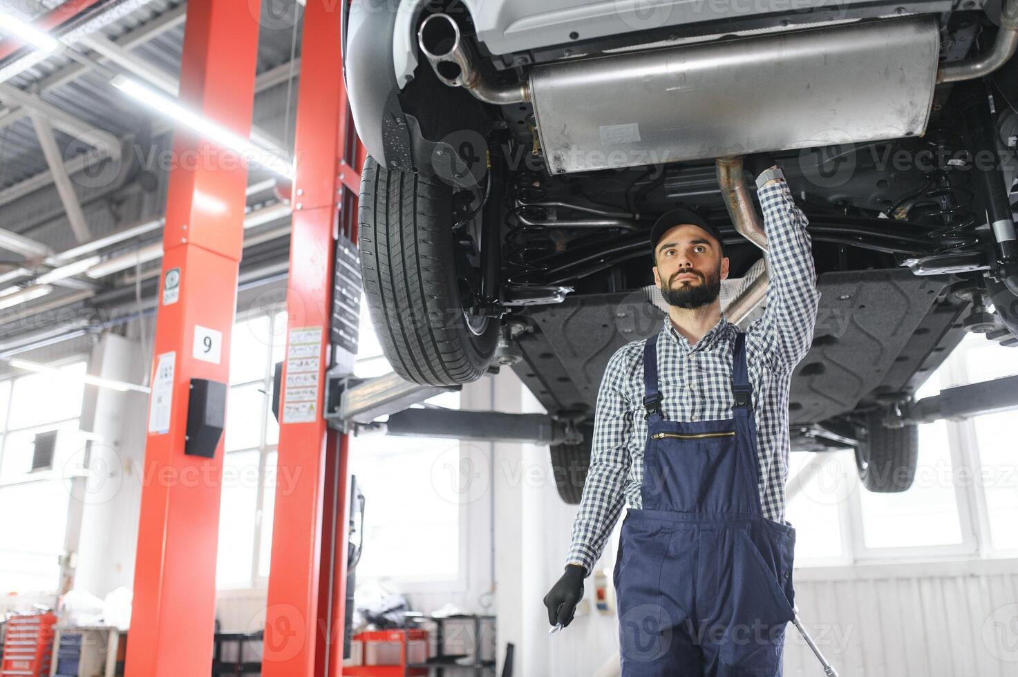 Handsome Car Mechanic is Posing in a Car Service. photo