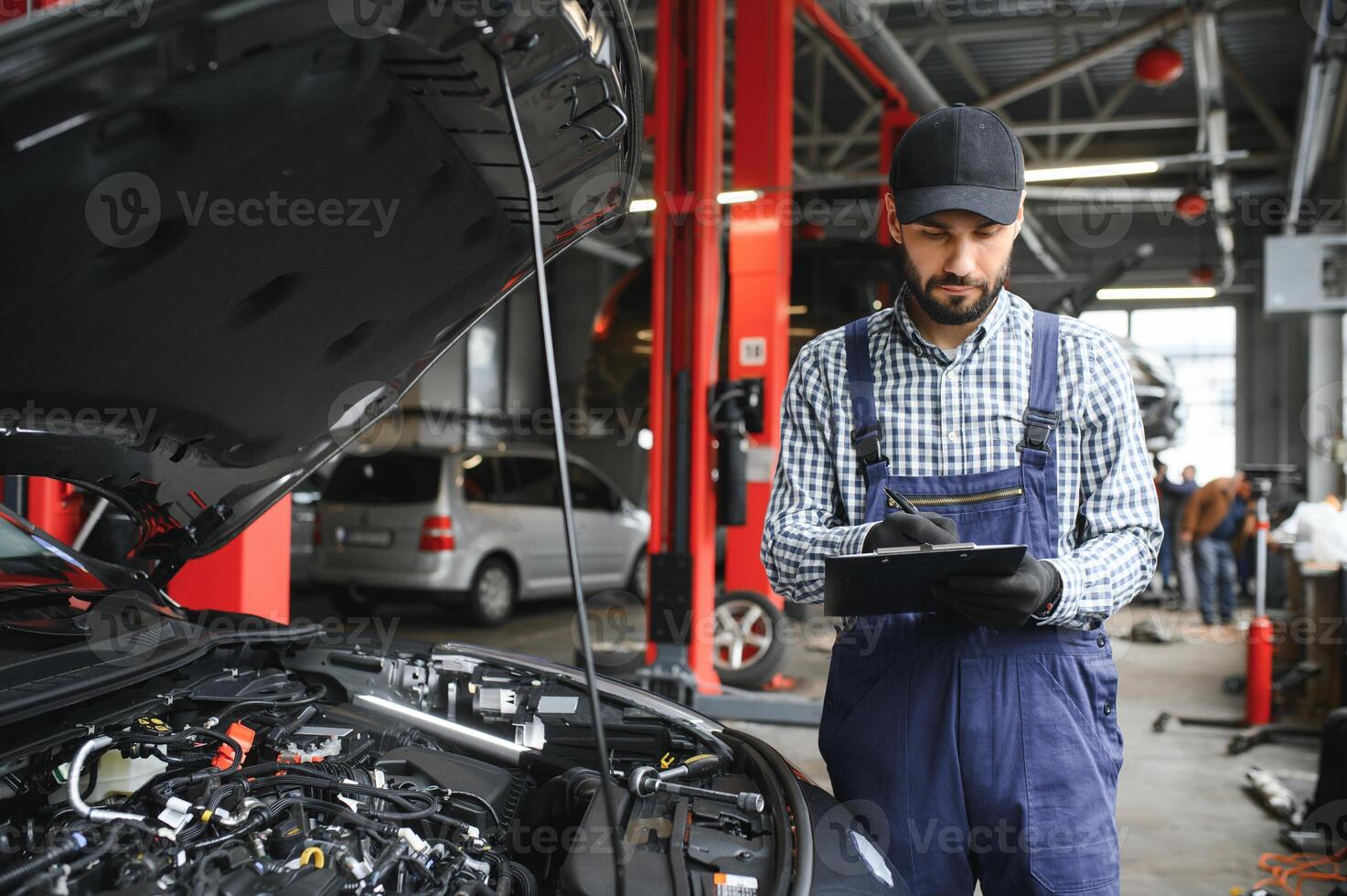 Professional caucasian car mechanic with checklist standing by vehicle engine area with hood open detecting malfunction photo