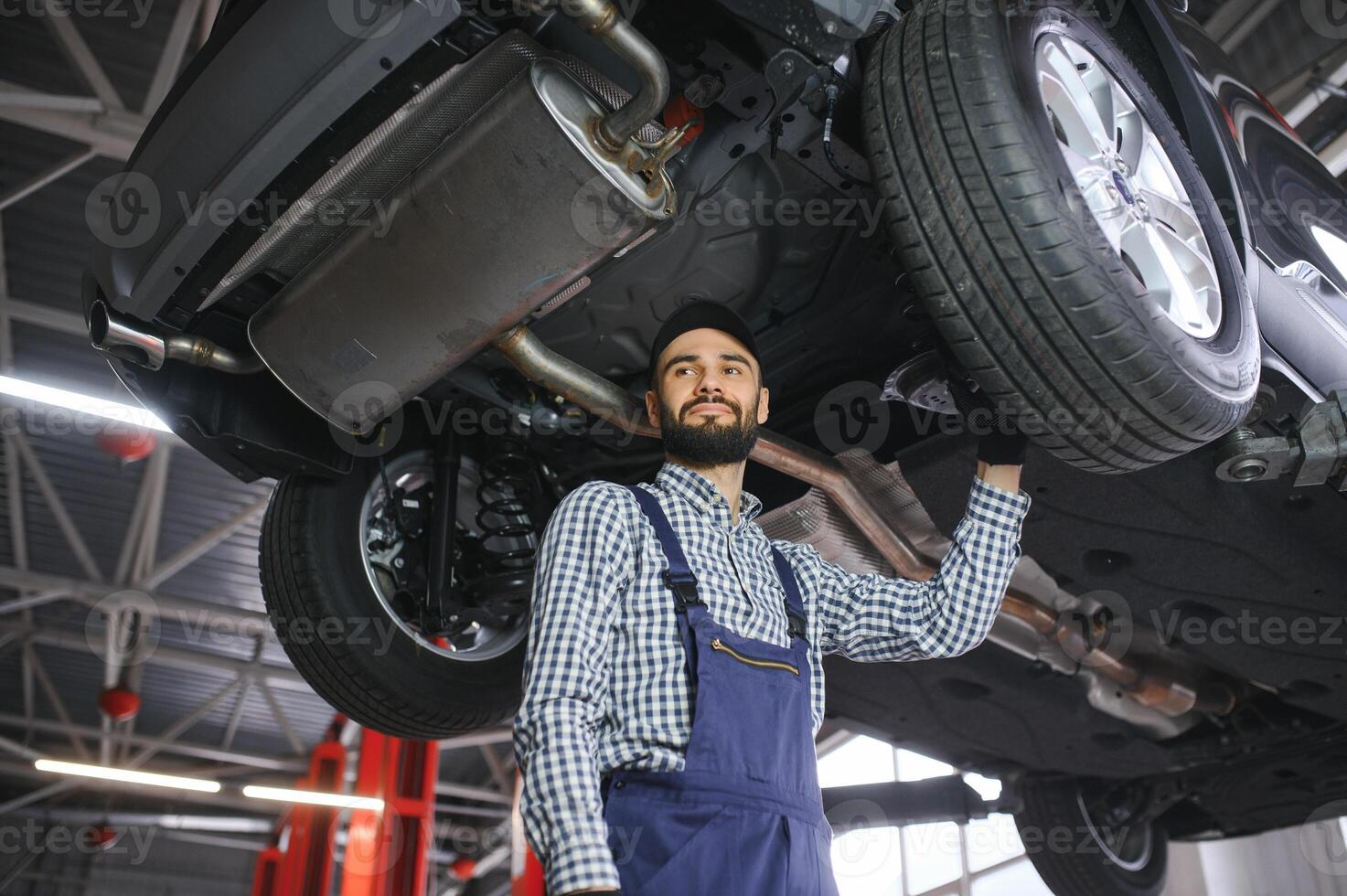 Portrait of a mechanic repairing a lifted car photo