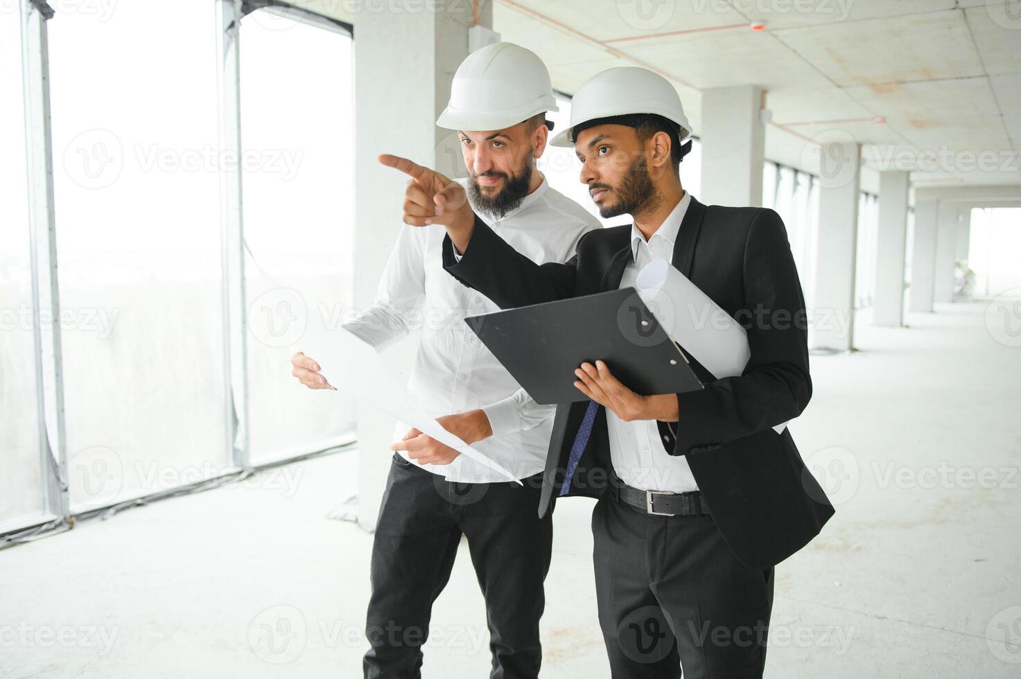 Indian and Arabian engineers. Contractor and architect talking about working on big project. Building in construction process interior. photo