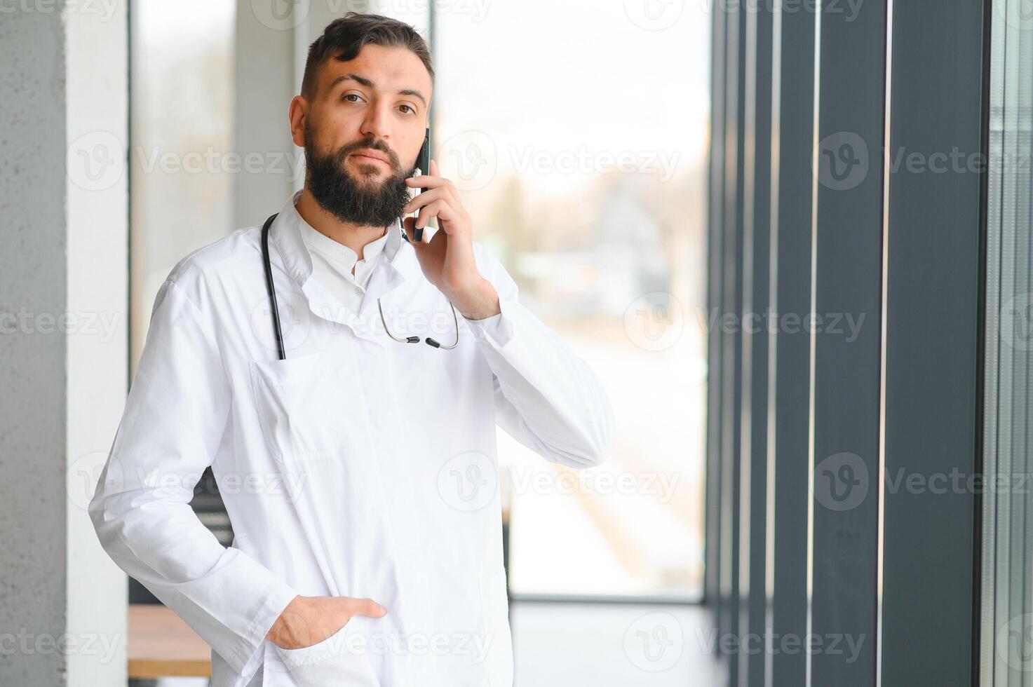 Portrait of pleasant young Arabian doctor in white coat. photo
