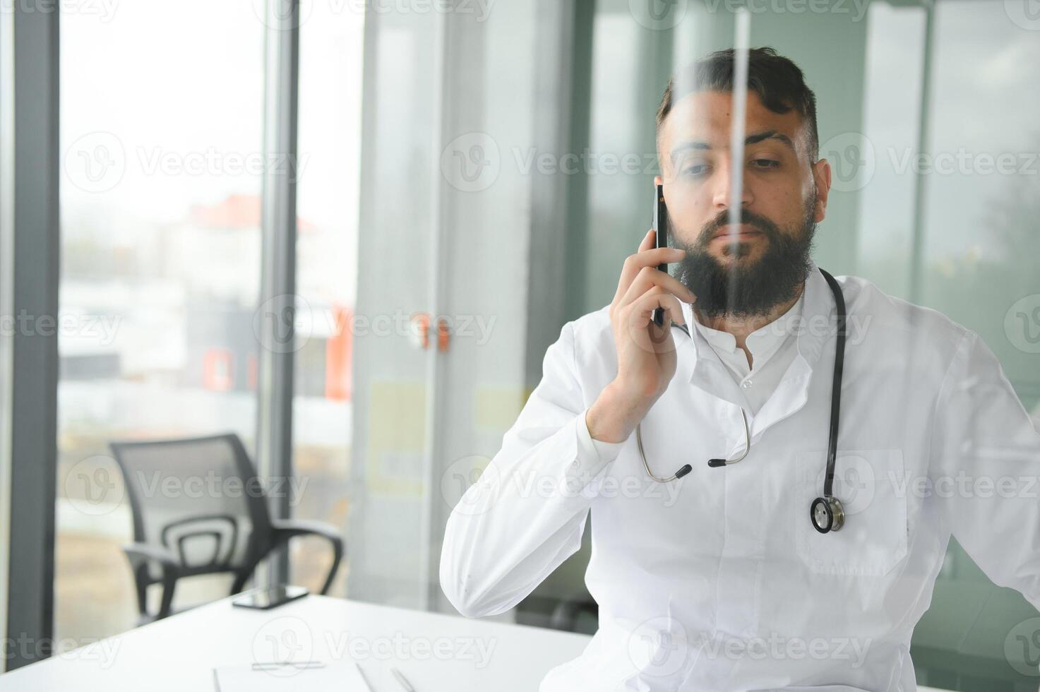 Portrait of pleasant young Arabian doctor in white coat. photo