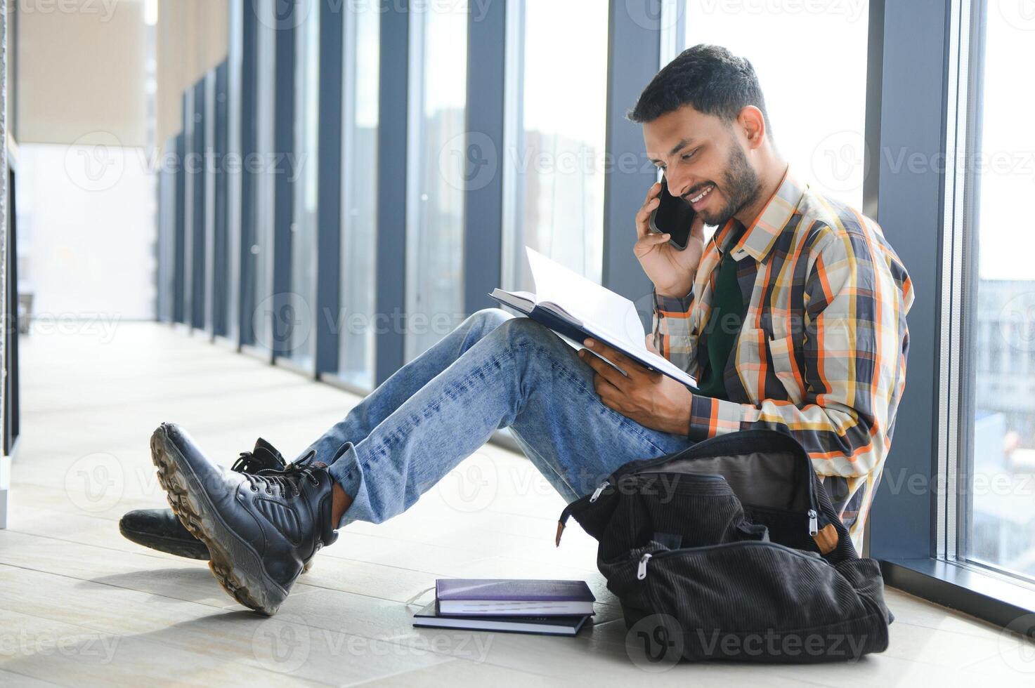 Handsome young Indian boy student with books and backpack at university. Education concept photo