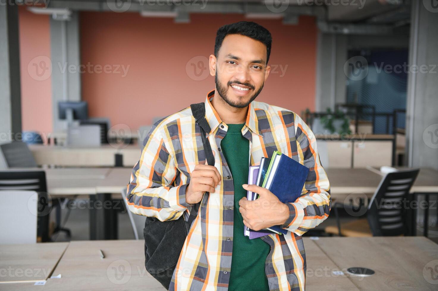 Handsome young Indian boy student with books and backpack at university. Education concept photo