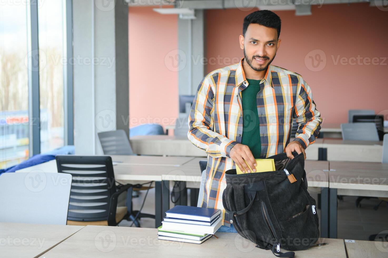 Young indian student boy reading book studying in college library with bookshelf behind. working on assignment or project photo