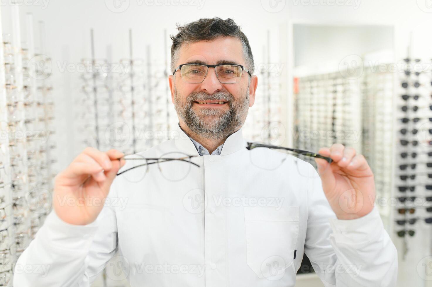 Handsome ophthalmologist holding eyeglasses for a try out. Optometrist offering to wear a pair of glasses. Image with small deph of field focused on the hands and glasses photo