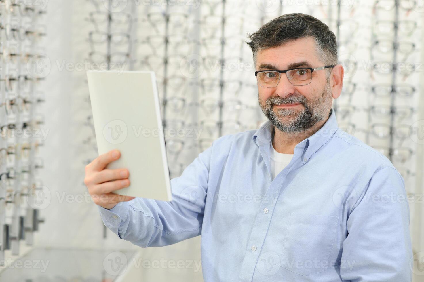 male customer choosing glasses in optics store photo