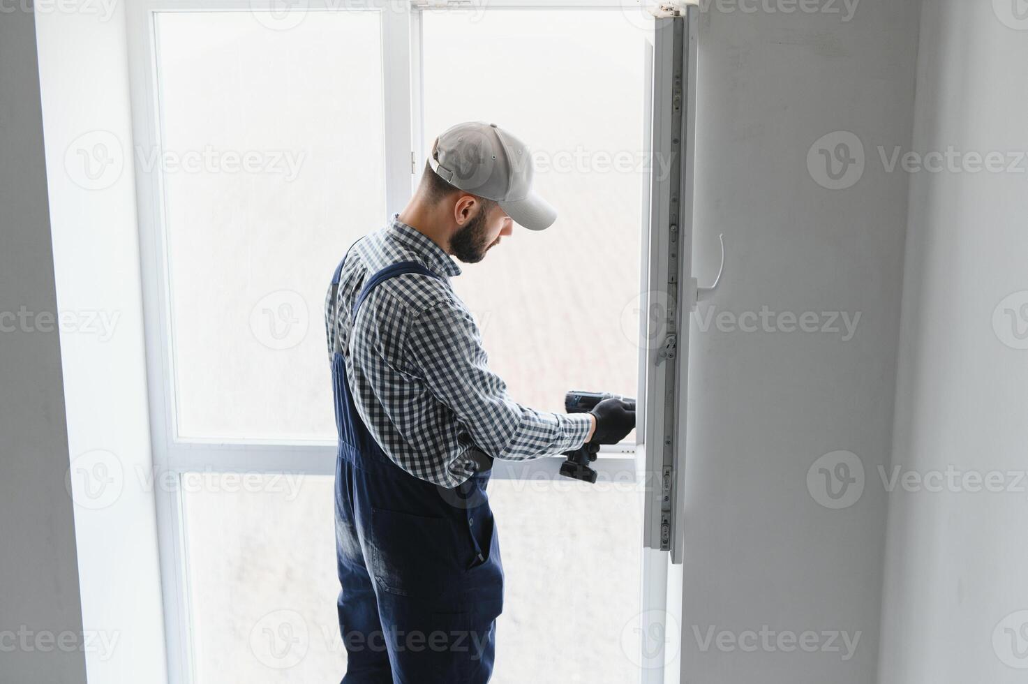 service man installing window with screwdriver photo
