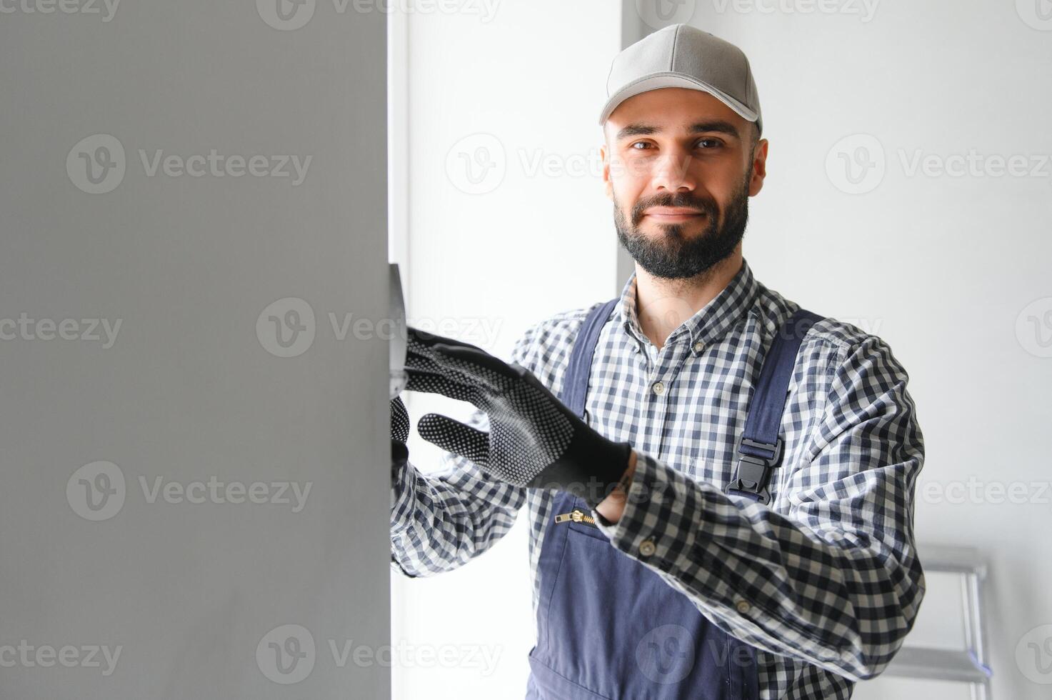 Plasterer in blue working uniform plastering the wall indoors photo