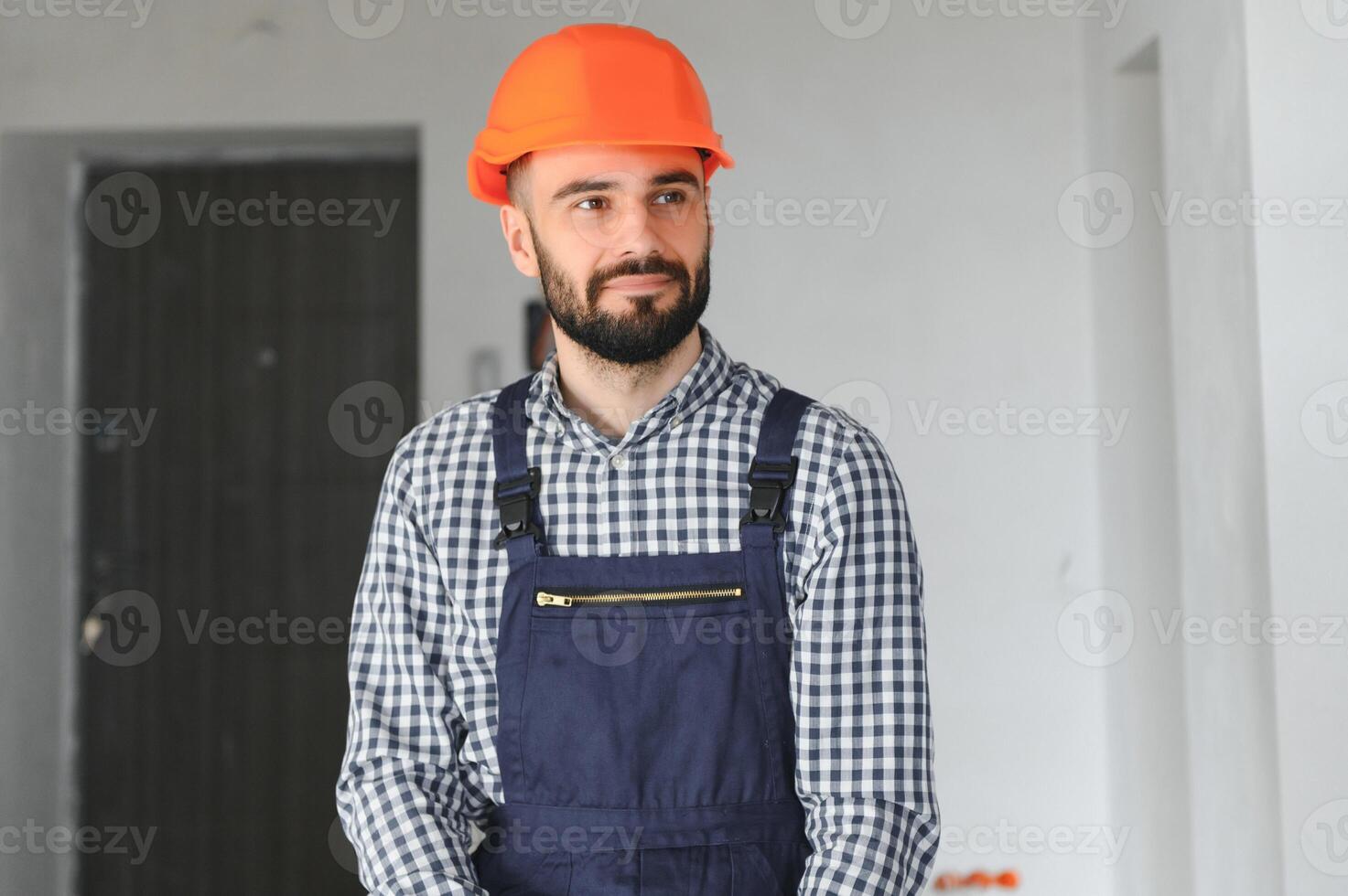 Portrait of positive, handsome young male builder in hard hat photo