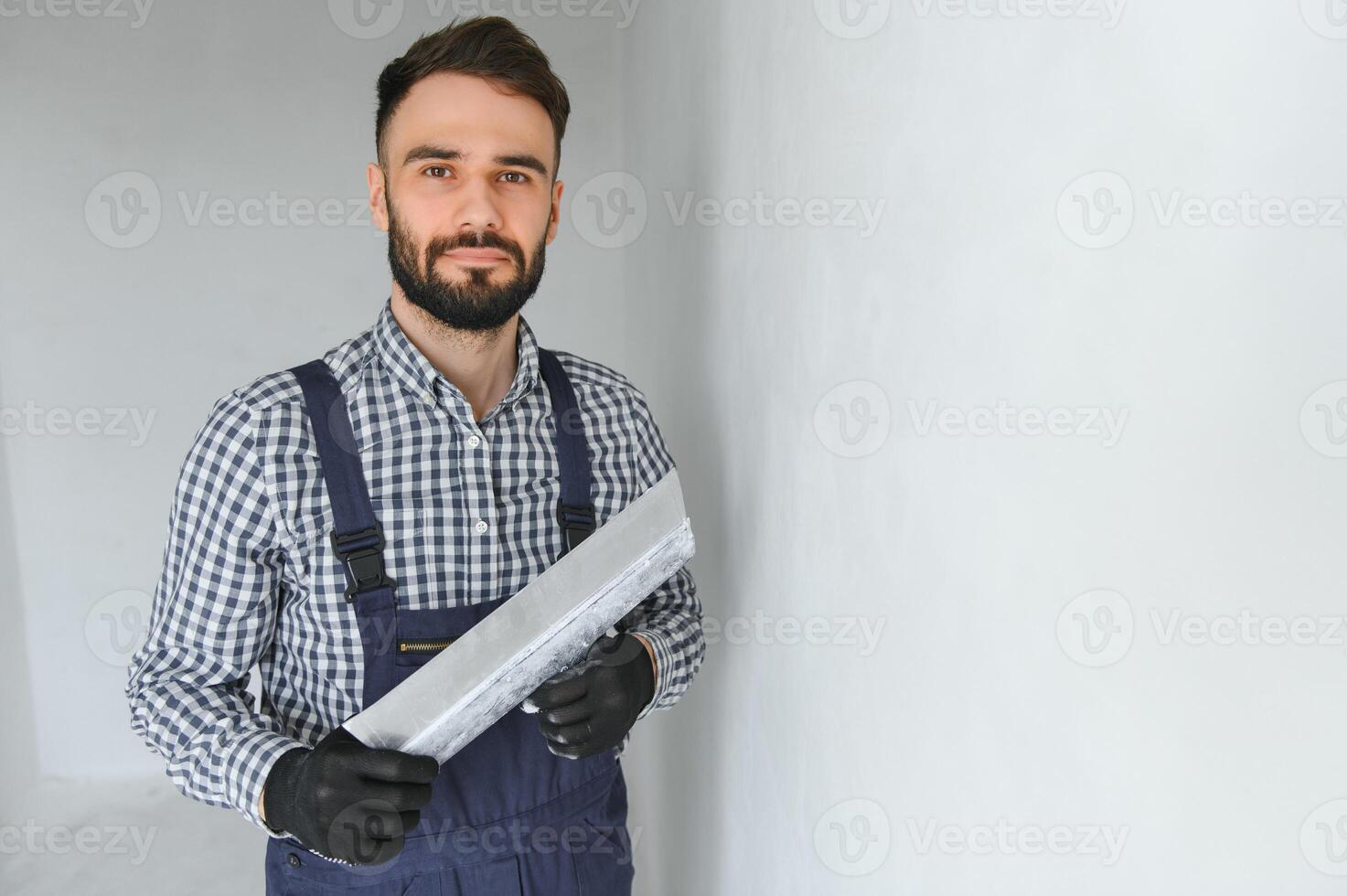 Portrait of handsome mechanic with stubble in blue overall, shirt having his arms crossed, looking at camera photo
