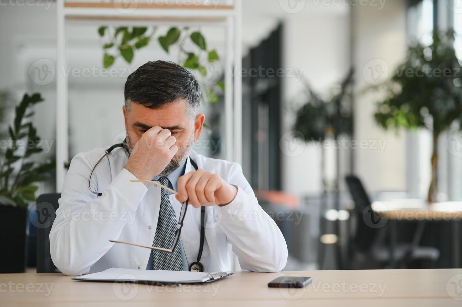 Senior caucasian man wearing doctor uniform and stethoscope at the clinic rubbing eyes for fatigue and headache, sleepy and tired expression. vision problem photo