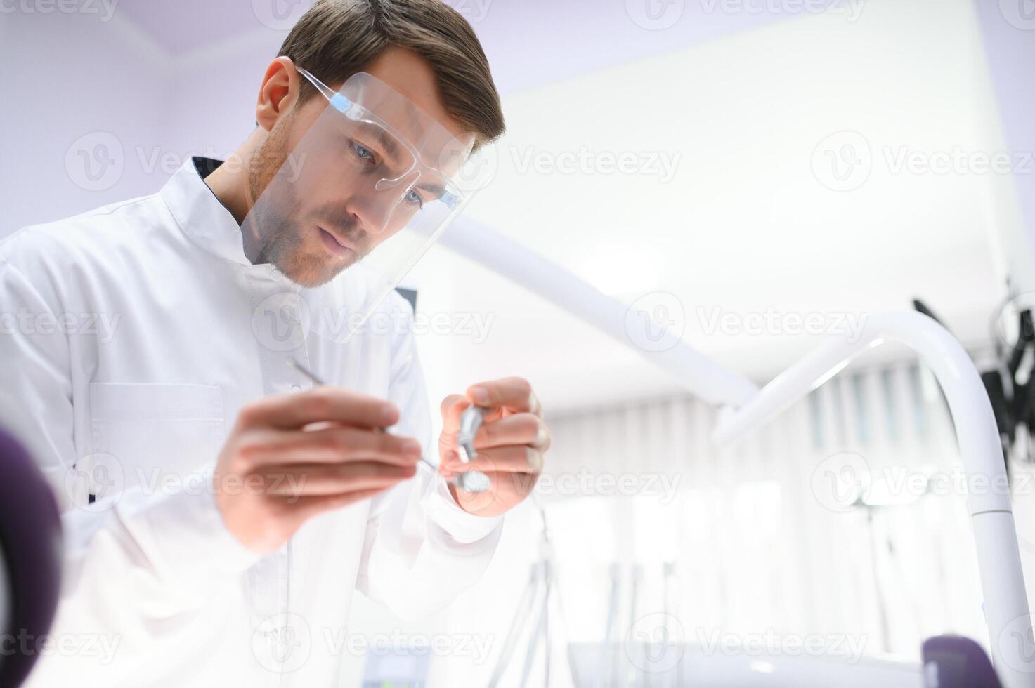 Bottom view. Dentist man with a tool in his hand. photo