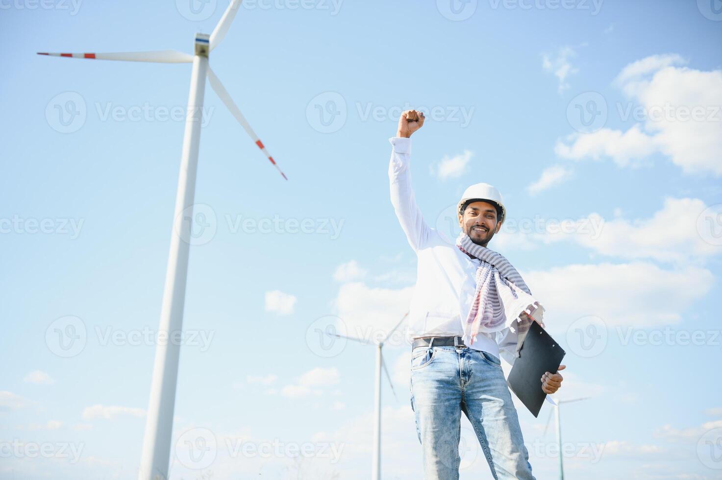 Engineer India man working at windmill farm Generating electricity clean energy. Wind turbine farm generator by alternative green energy. Asian engineer checking control electric power photo
