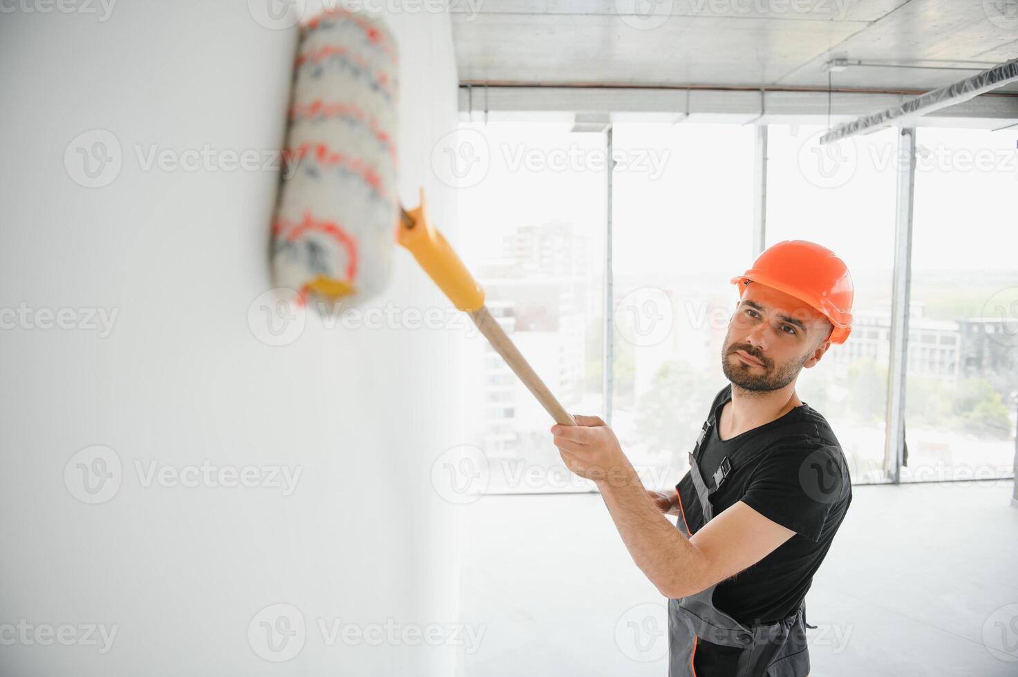 The man is painting the wall. DIY repair. The painter holds the roller near the wall photo