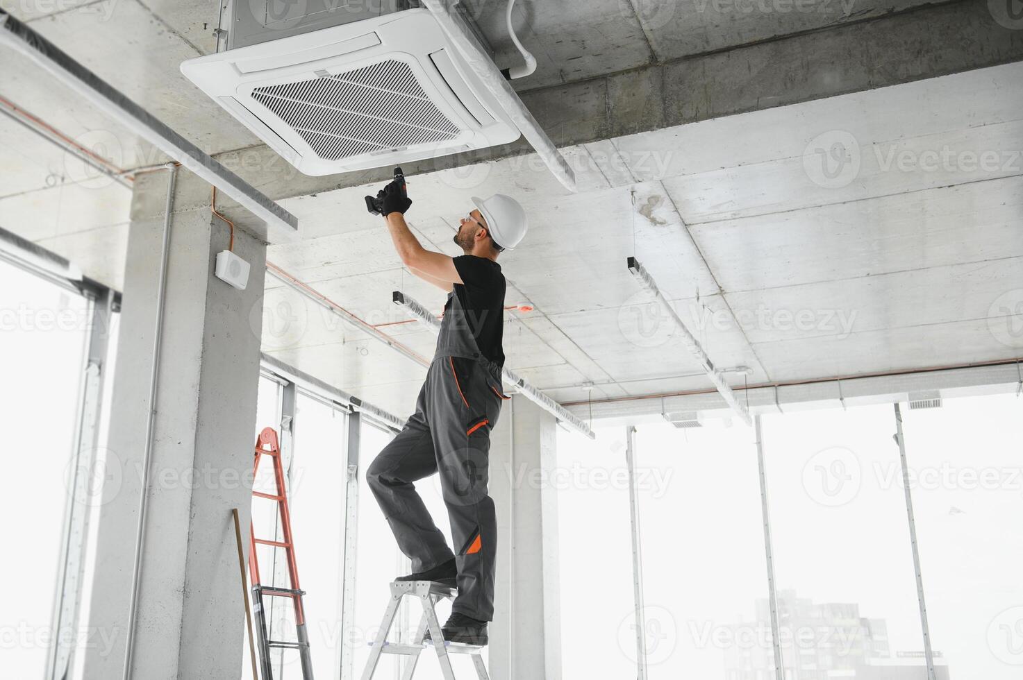 Worker repairing ceiling air conditioning unit photo