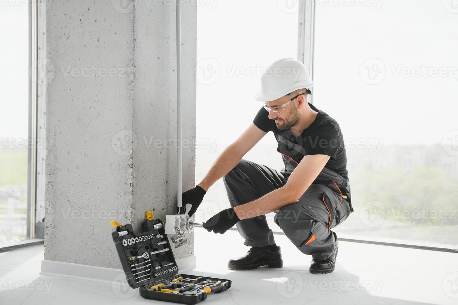 electrician installs socket boxes on the wall and puts a putty on them photo