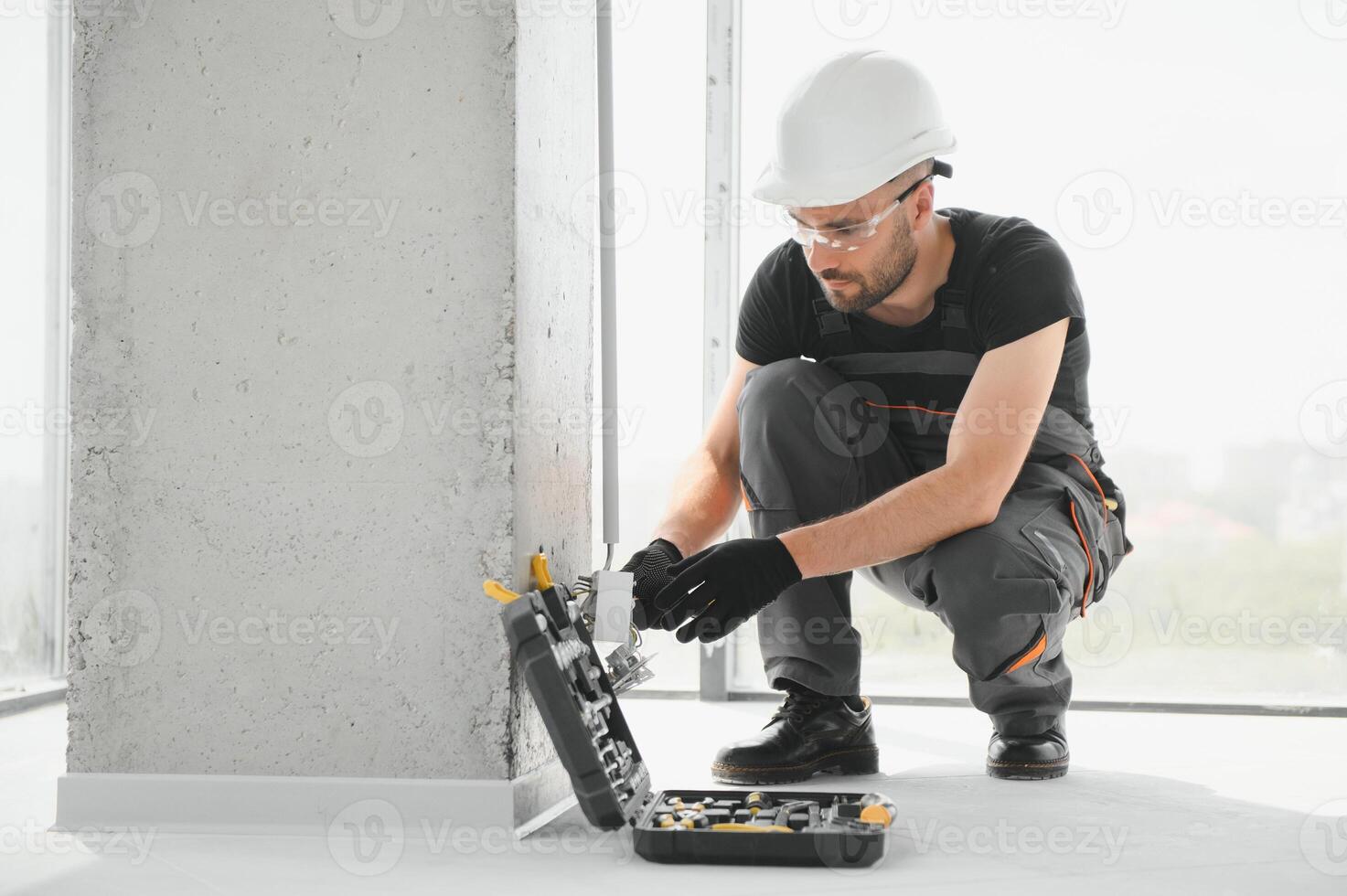 electrician installs socket boxes on the wall and puts a putty on them photo