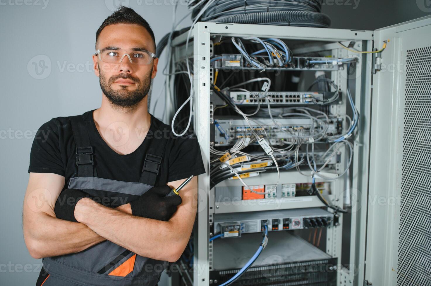 Young man is working with internet equipment and wires in server room photo