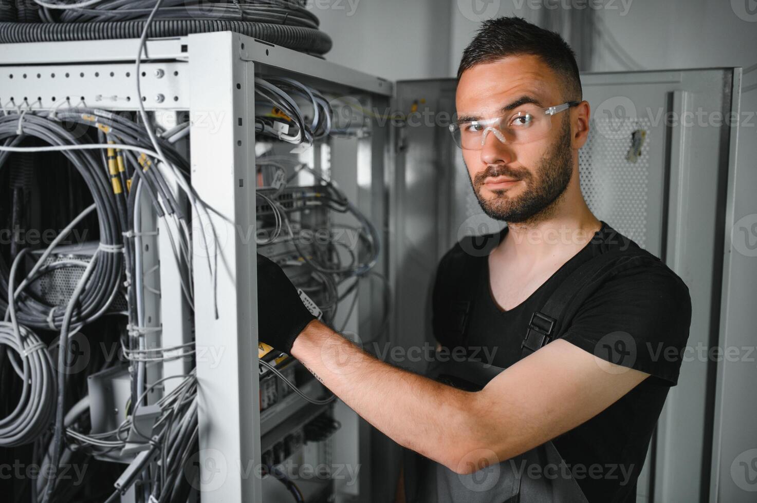 Young man is working with internet equipment and wires in server room photo