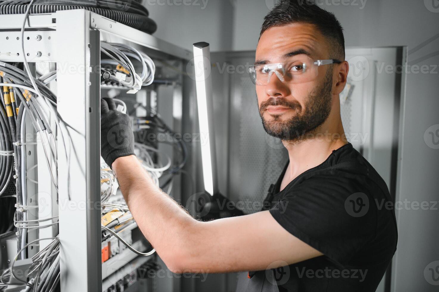 Repairman is busy and working with internet equipment and wires in server room photo