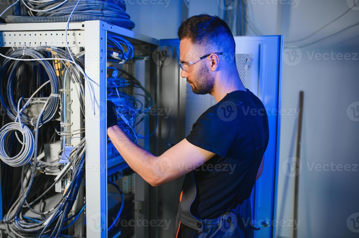 A technician works with server equipment in a data center. A man commutes wires in a server room photo