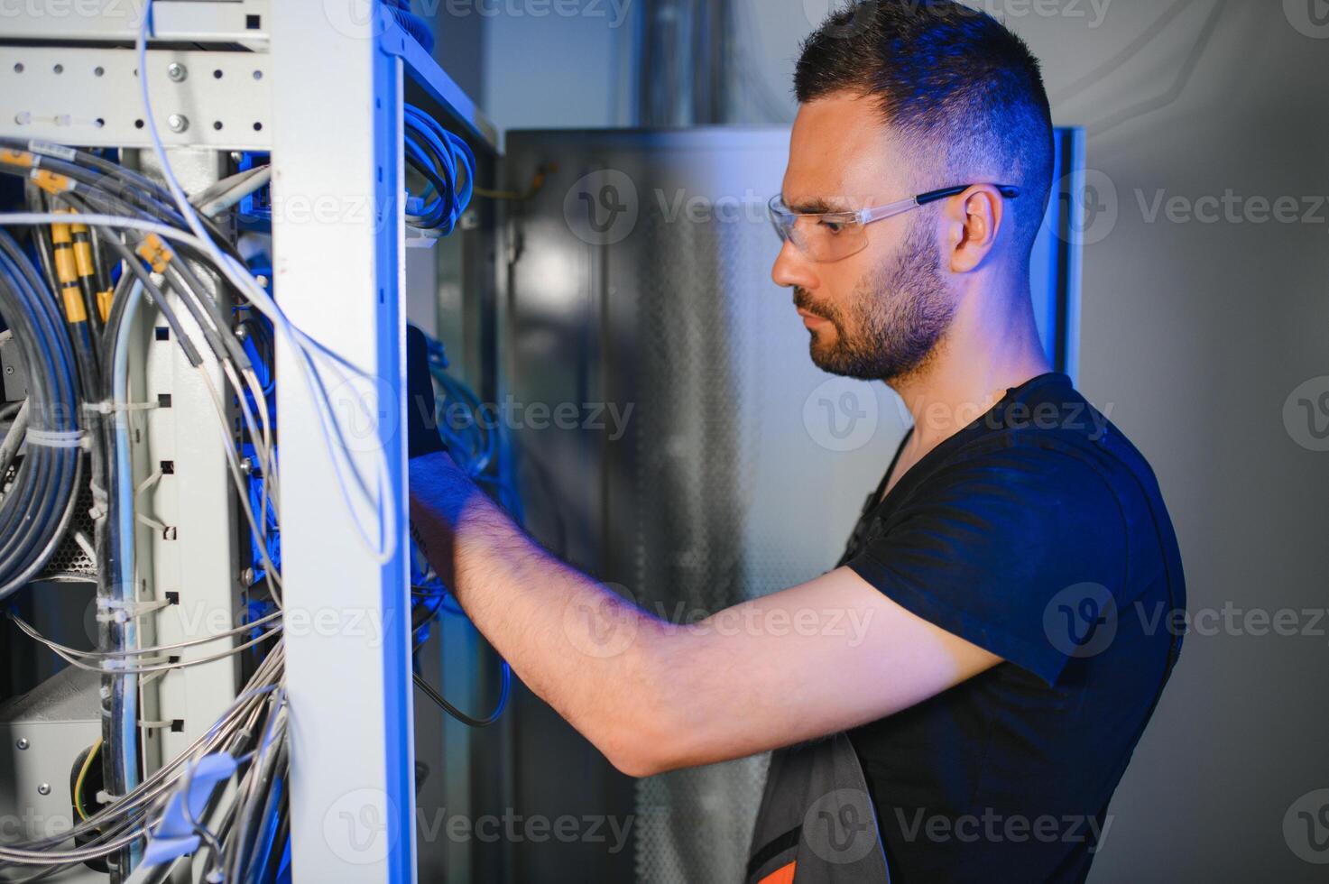 Repairman is busy and working with internet equipment and wires in server room photo