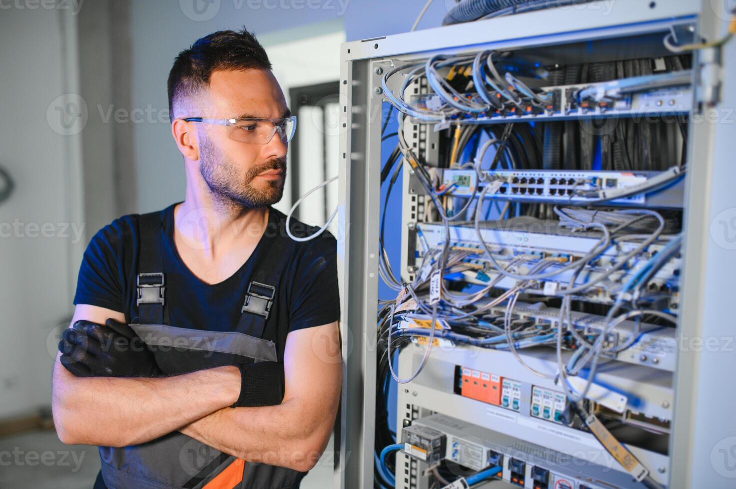 A technician works with server equipment in a data center. A man commutes wires in a server room photo