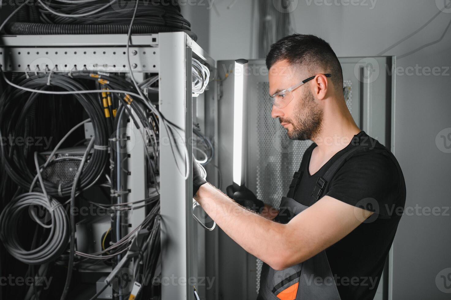 A technician works with server equipment in a data center. A man commutes wires in a server room photo