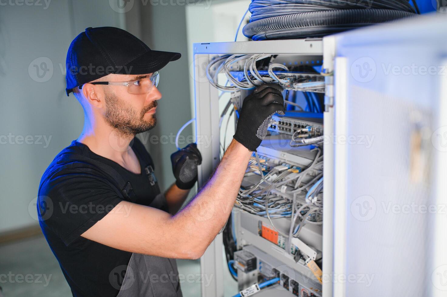 Young man is working with internet equipment and wires in server room photo