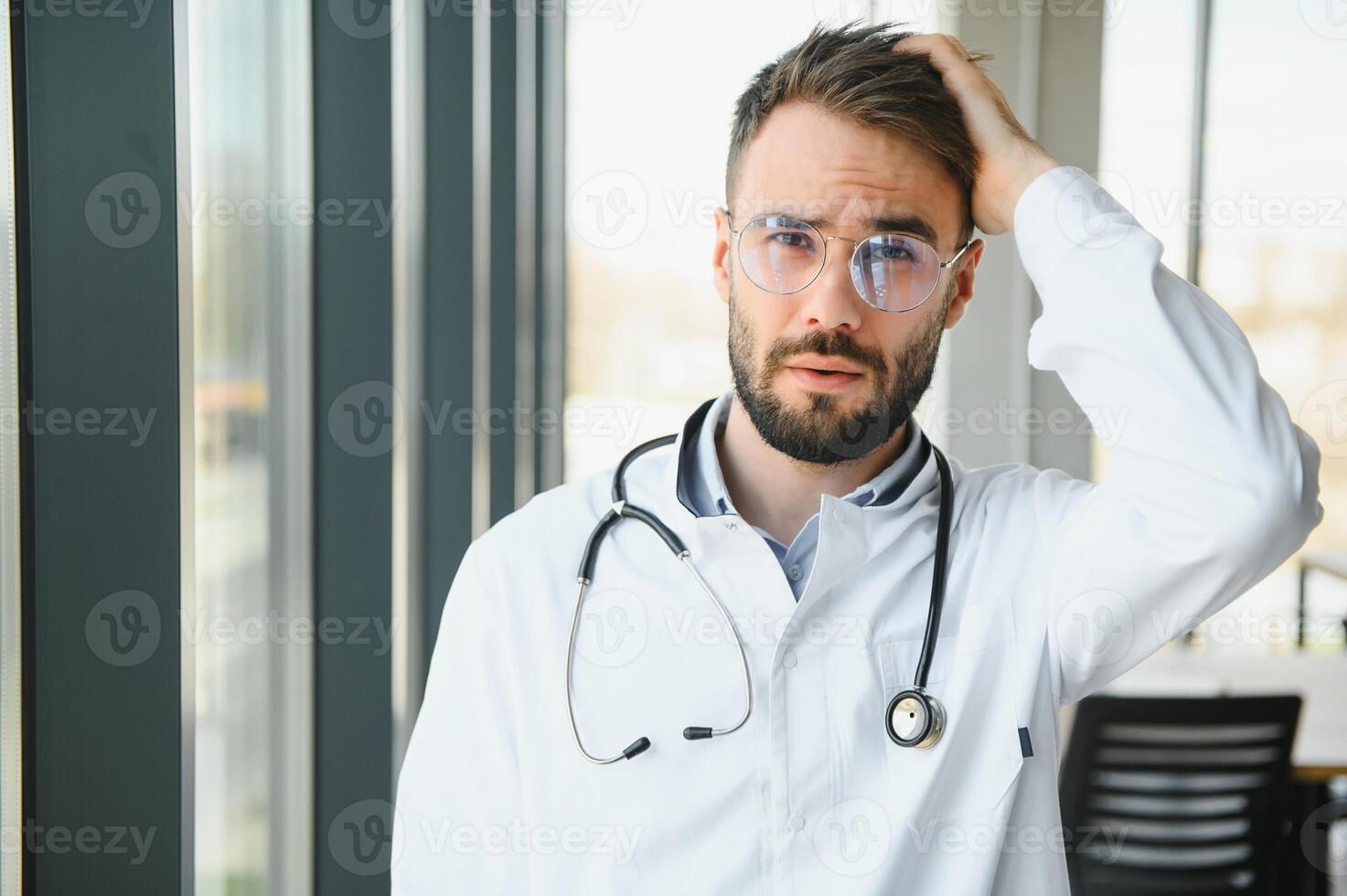 Stressed male doctor. Mid adult male doctor working long hours. Overworked doctor in his office. Not even doctors are exempt from burnout photo