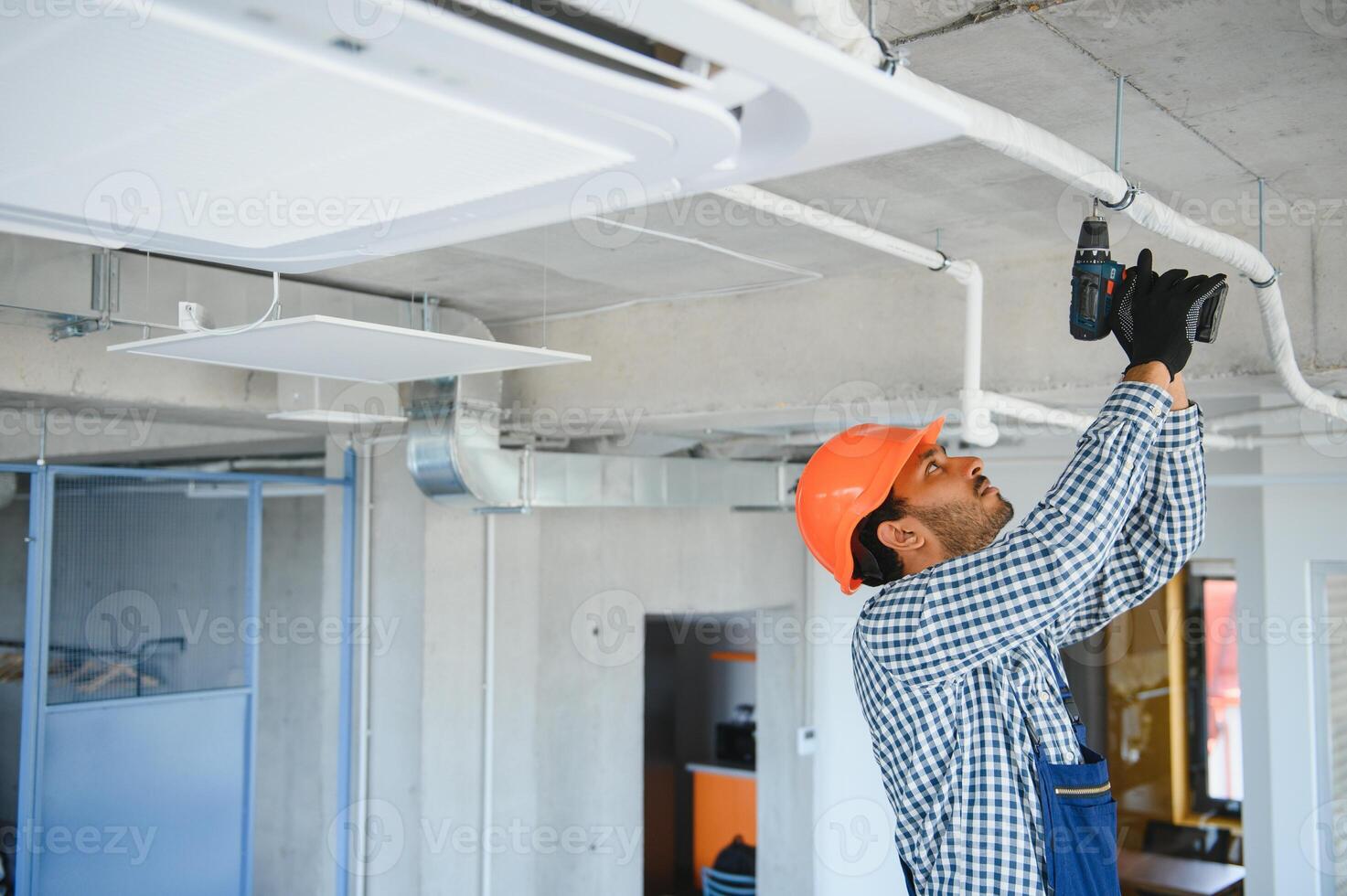 Concentrated young Indian engineer setting up air conditioner. photo