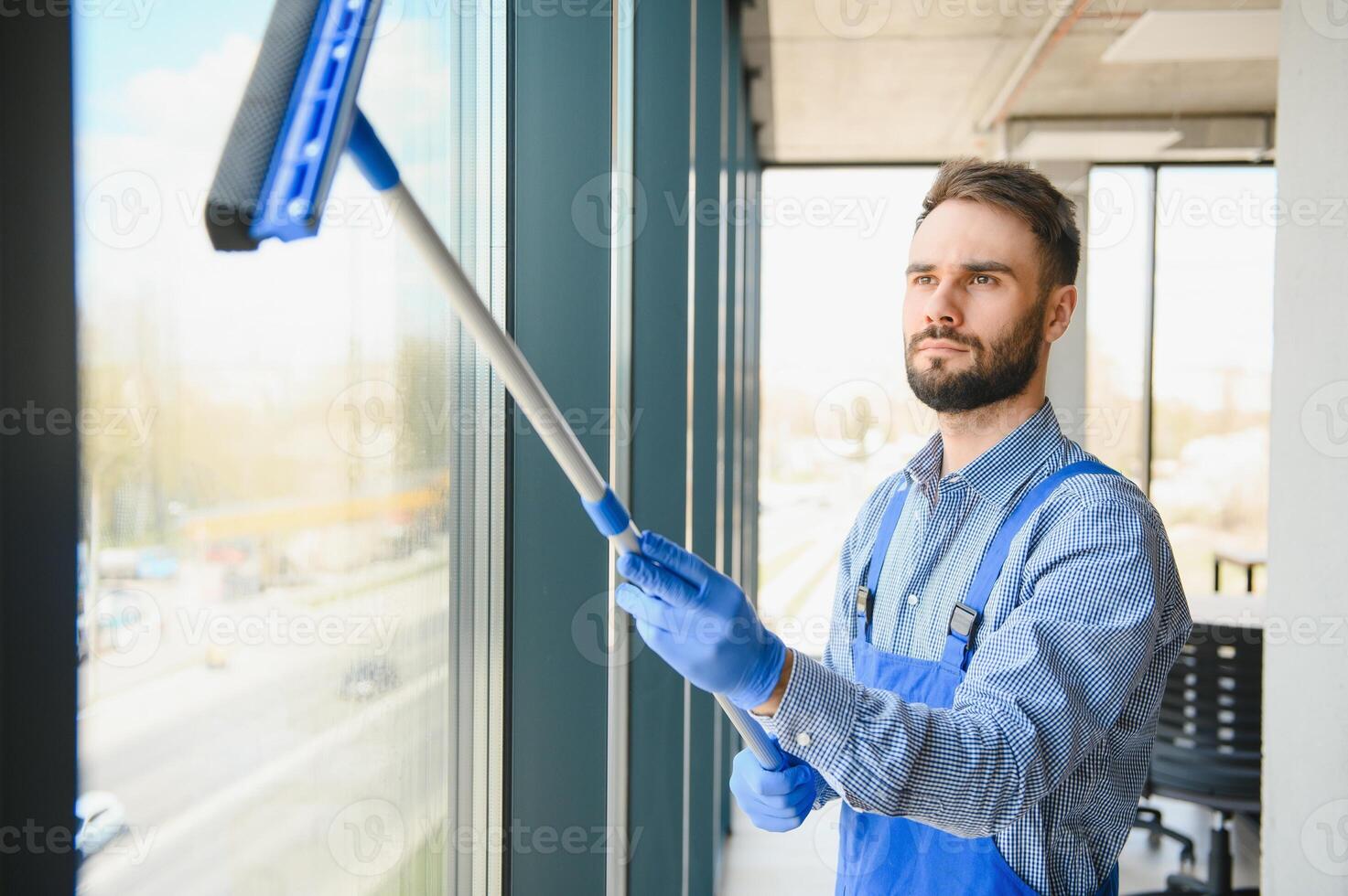 Young man cleaning window in office photo