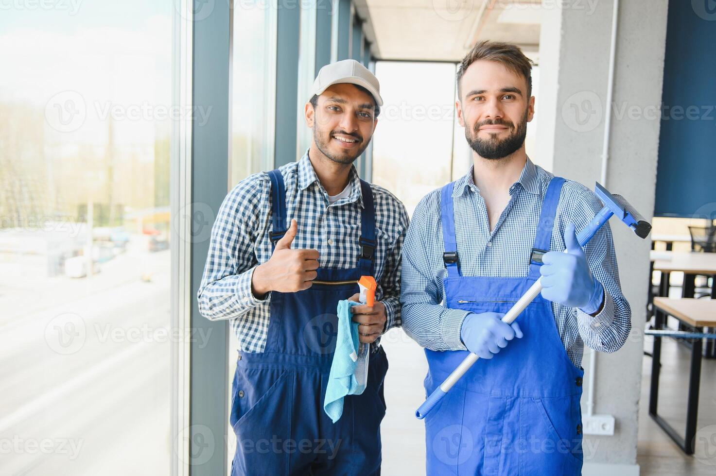 multiethnic professional cleaners in uniform washing large windows in office photo