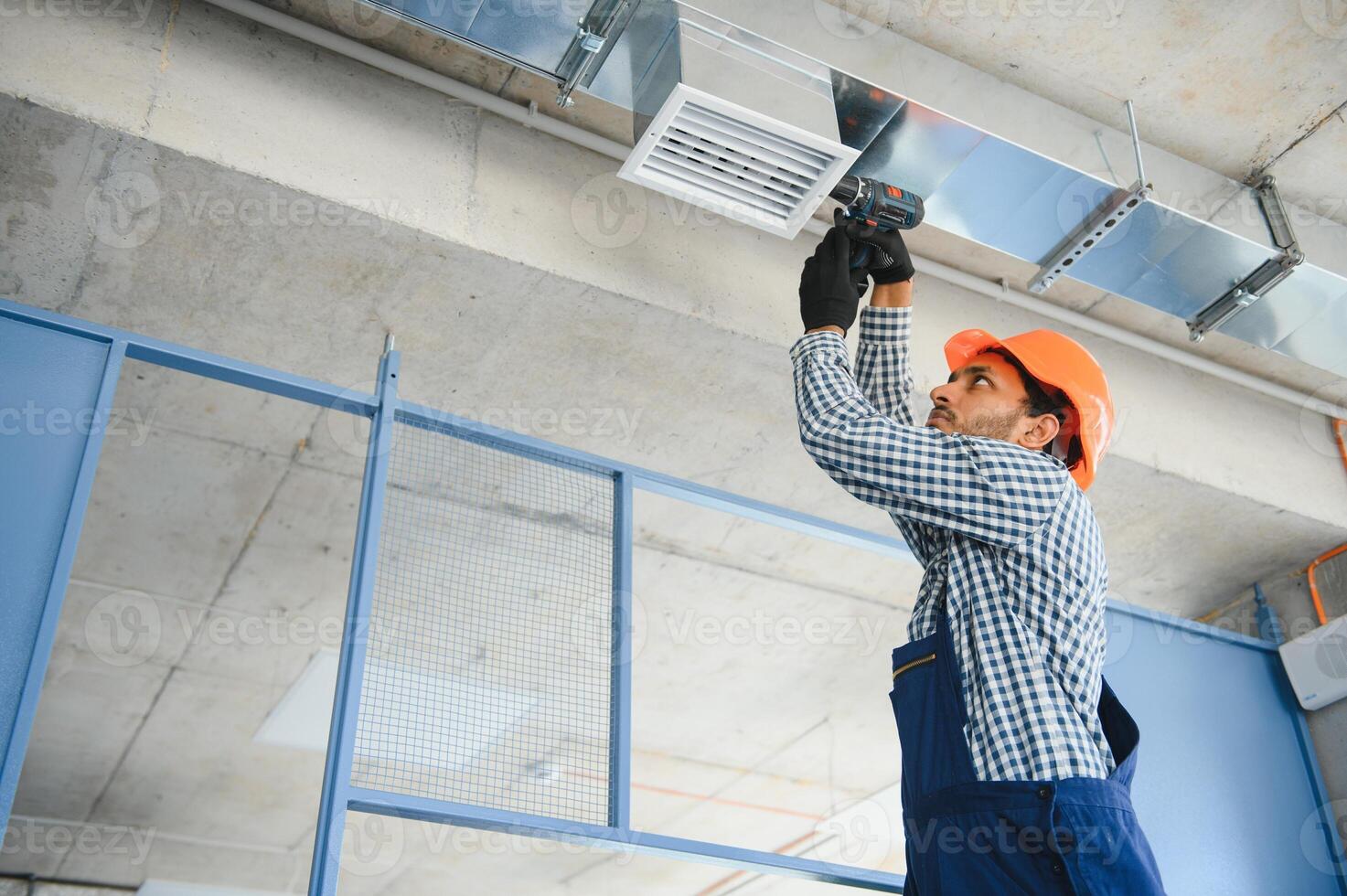 hvac indian worker install ducted pipe system for ventilation and air conditioning. copy space photo