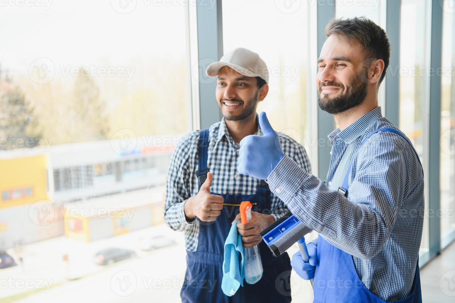 multiethnic professional cleaners in uniform washing large windows in office photo