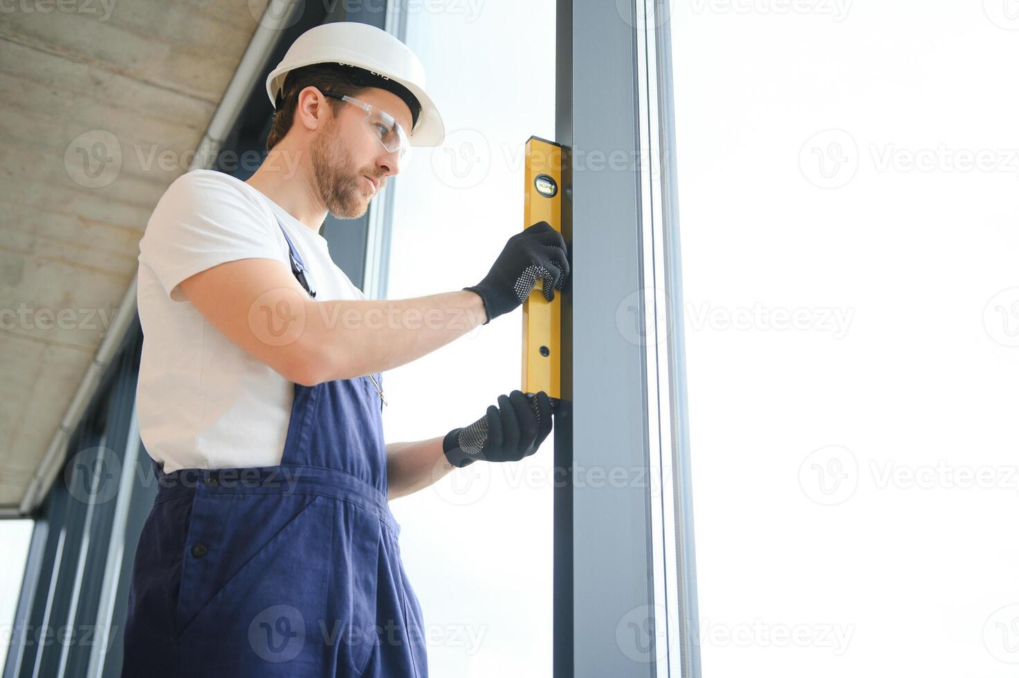 Worker using bubble level after plastic window installation indoors photo