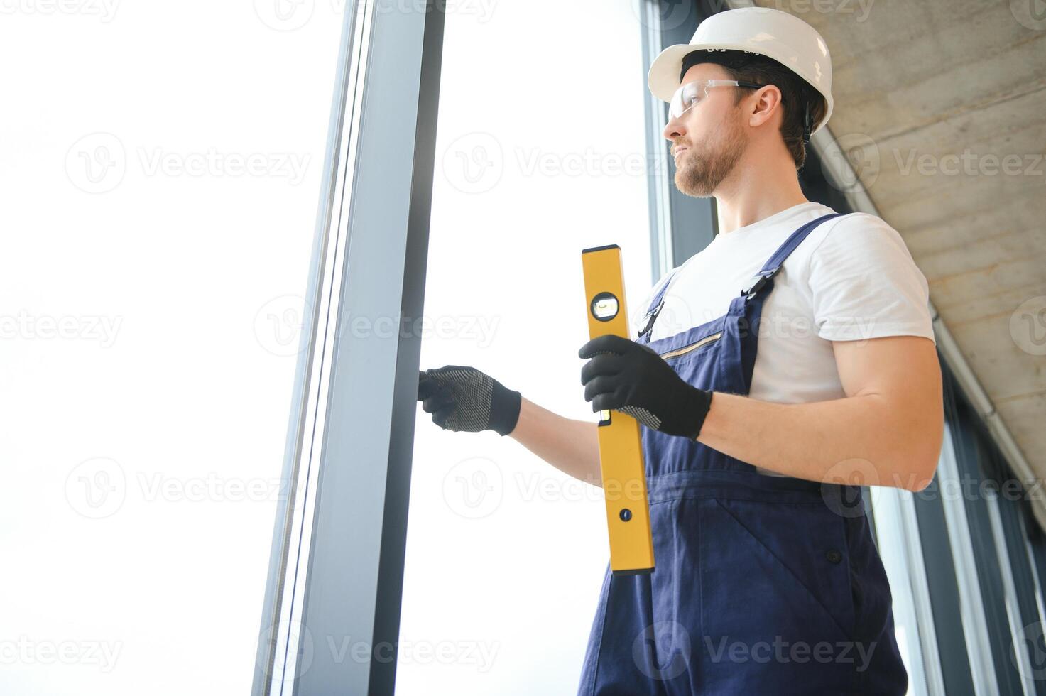 Worker using bubble level after plastic window installation indoors photo
